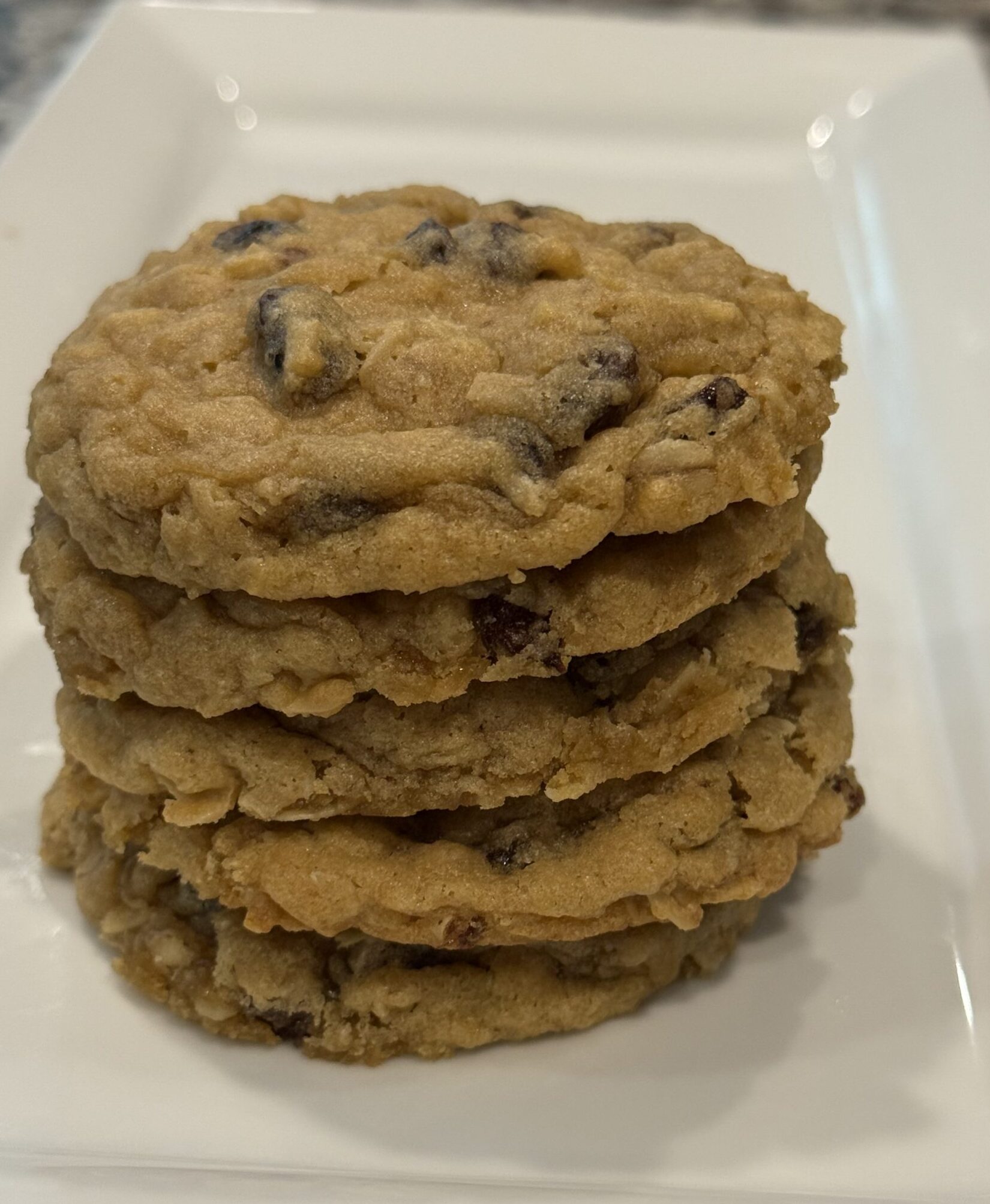 Close-up of soft and chewy oatmeal raisin cookies stacked on a cooling rack, with golden edges and raisins peeking through the dough.