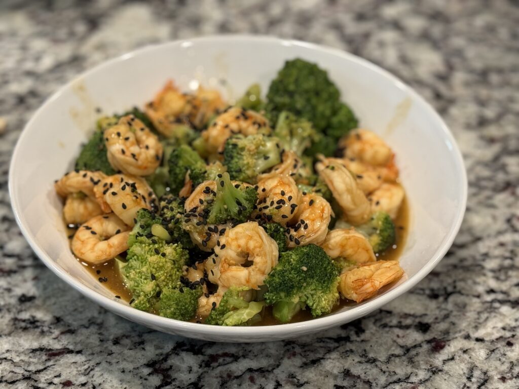 Shrimp and broccoli stir fry in a skillet with sesame seeds on top