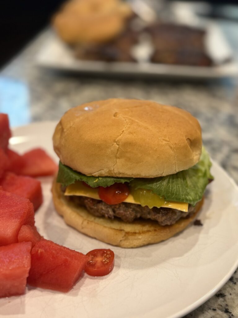 Juicy smash burgers cooking on a Blackstone griddle, topped with melted cheese and served with fresh toppings on toasted buns.