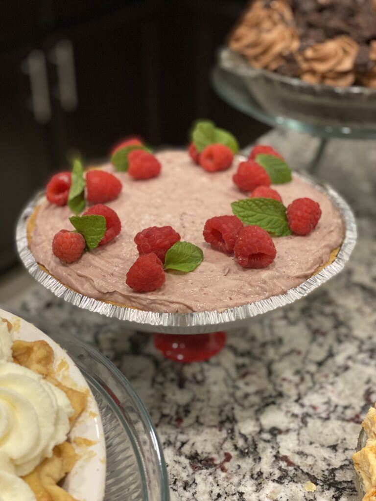 rozen raspberry cream pie topped with whipped cream and fresh berries