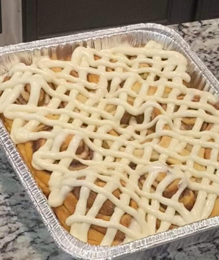 Pan of soft cinnamon rolls with cream-cheese frosting melting into the swirls