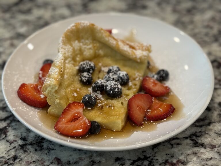 Slice of Dutch baby topped with blueberries and syrup
