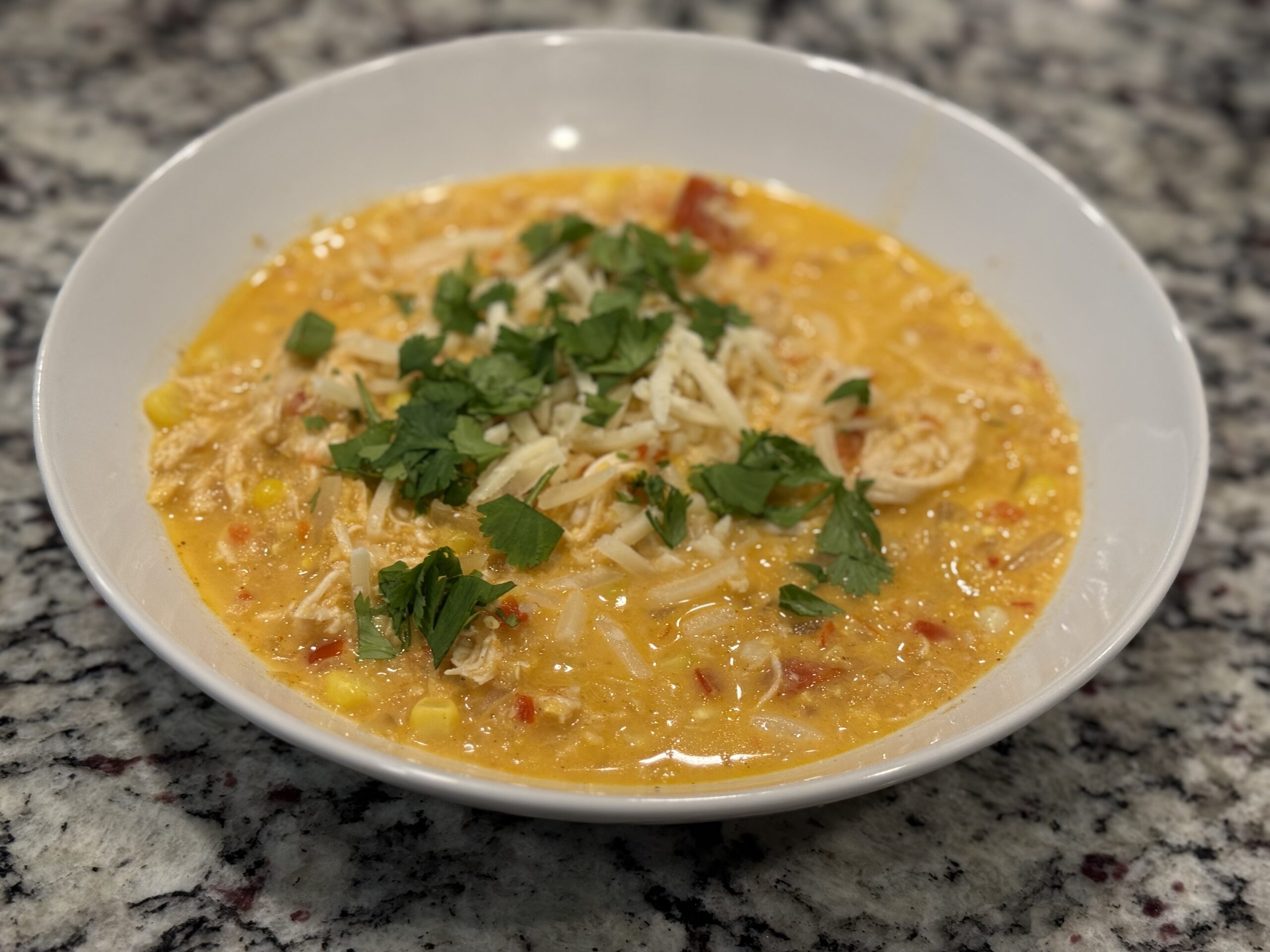 Bowl of Mexican Corn Chicken Soup topped with Monterey Jack and cilantro