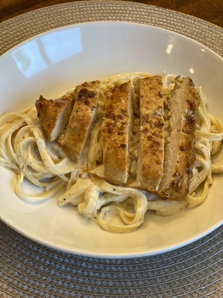 Sliced garlic chicken served over creamy pasta