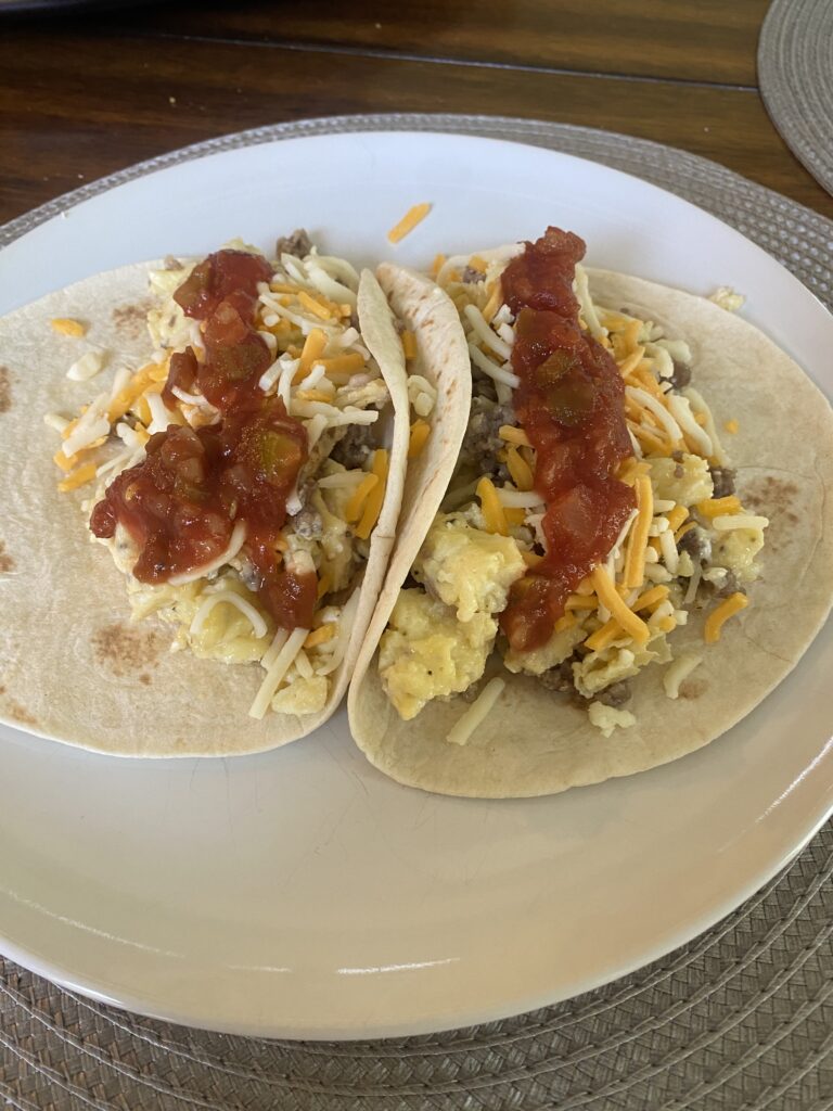 Close-up of a warm taco filled with eggs, sausage, and melted cheese