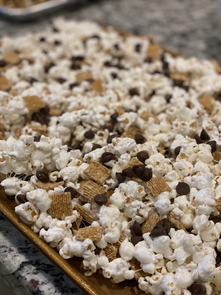 Close-up of gooey S’mores Popcorn mixed with Golden Grahams, marshmallow coating, and chocolate chips.