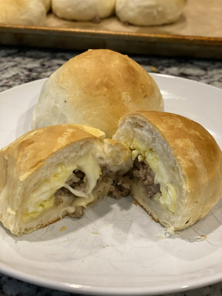Breakfast Bomb cut open to show sausage, scrambled eggs, and melted cheese wrapped inside a golden biscuit.