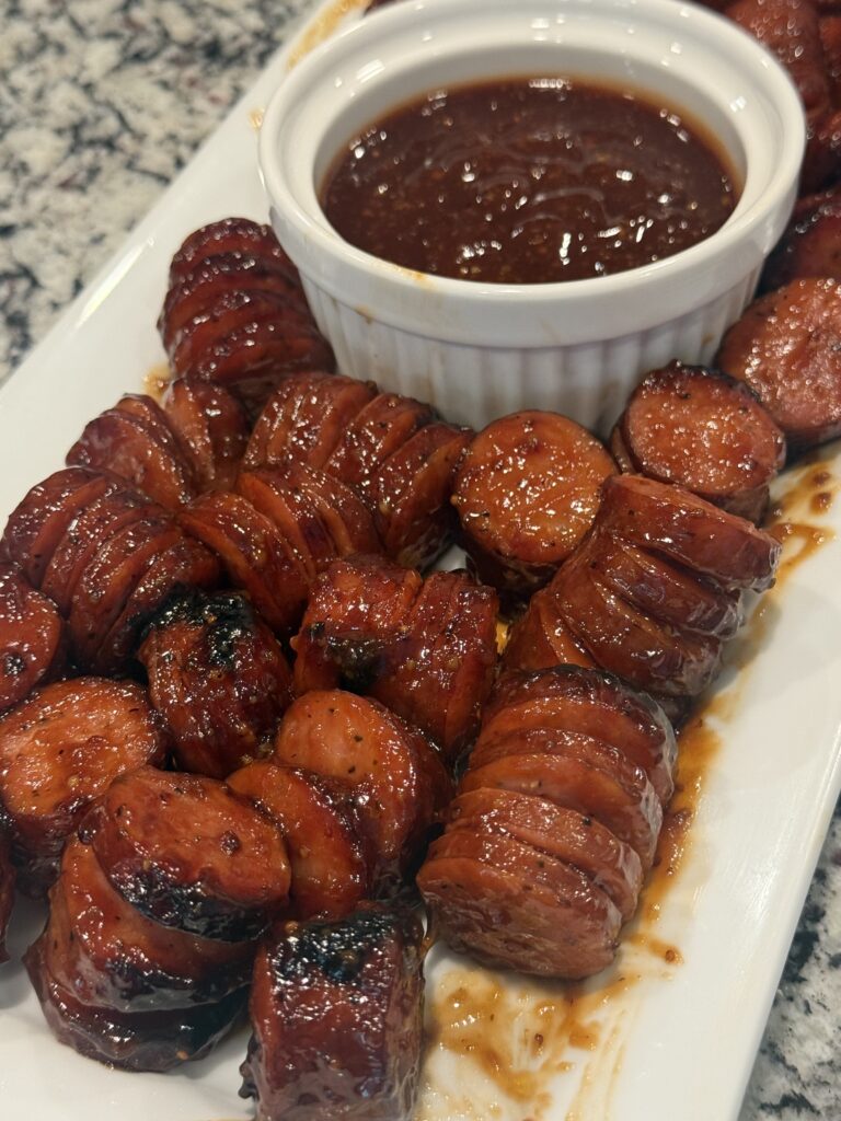 Maple BBQ smoked sausage bites baked in the oven, glazed with sweet barbecue sauce and served with toothpicks on a platter