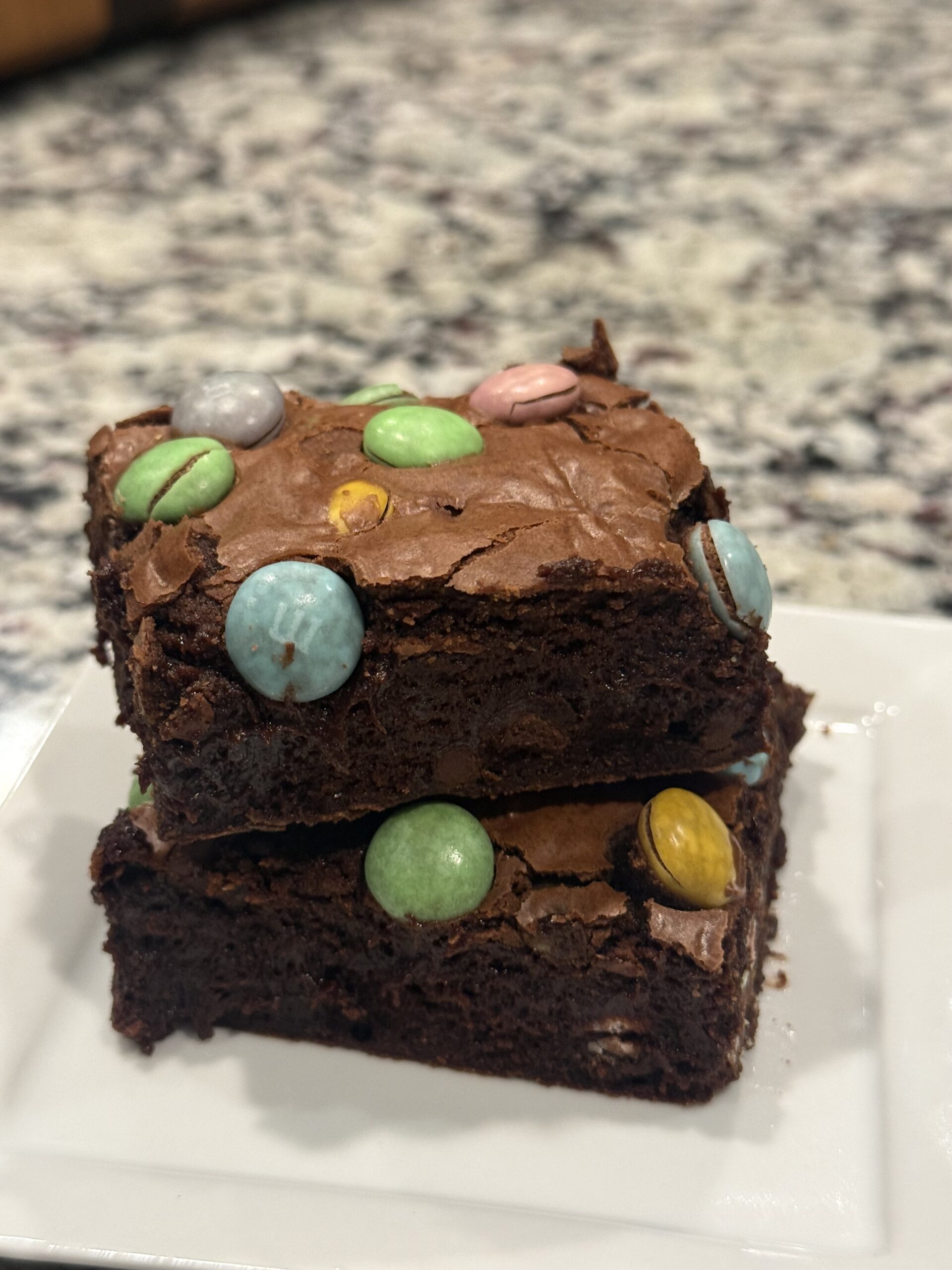 Thick fudgy M&M brownies with a crackly top, chocolate chips, and colorful M&M candies baked in an 8x8 pan.